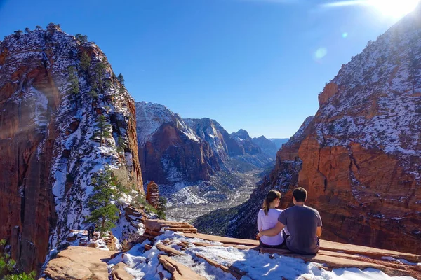 SUN FLARE : Un couple de randonneurs s'assoit sur une corniche et observe le canyon hivernal — Photo