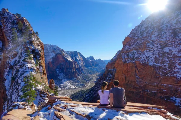 LENS FLARE : Un couple de randonneurs s'assoit sur une corniche et observe le canyon hivernal — Photo