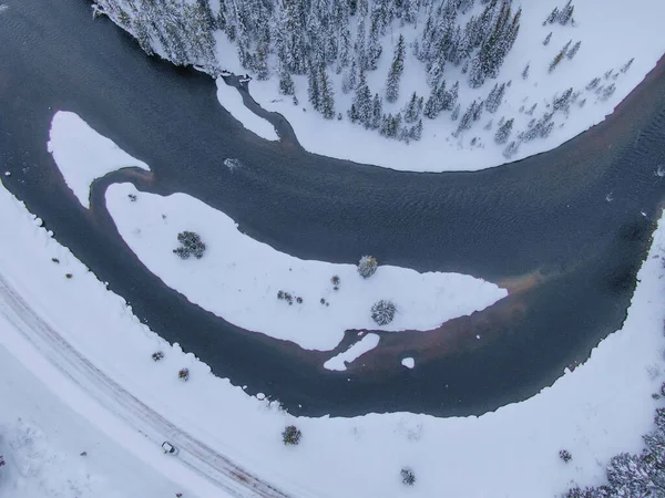 하얀 차가 굽어 지는 강을 따라 눈덮인 도로를 따라 달리고 있다. — 스톡 사진