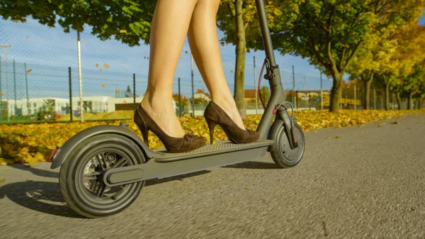 FERMER : Une femme d'affaires moderne se rend au travail sur un scooter électrique cool. — Photo