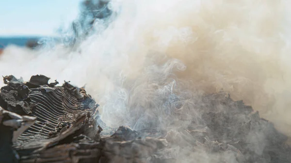 Un primo piano di nuvole di fumo che escono da un mucchio di cartone in fiamme. — Foto Stock