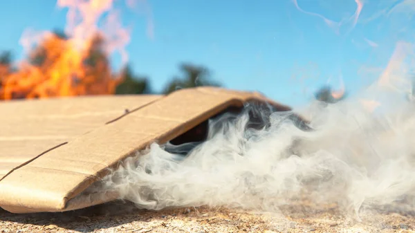 MACRO: Pedaço de papelão residual é deixado para queimar no chão ao ar livre . — Fotografia de Stock