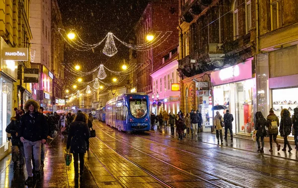 Pedestres caminham ao longo da rua festiva em Zagreb enquanto o bonde atravessa a cidade — Fotografia de Stock