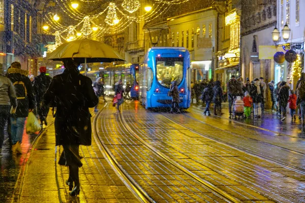 Voetgangers steken feestelijke winkelstraat in voordat tram rijdt door de stad — Stockfoto