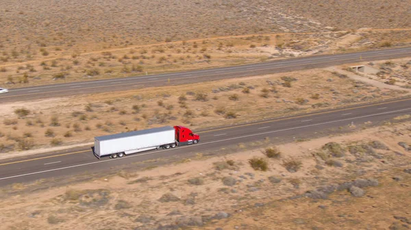 AERIAL: Vliegen boven een rode vrachtwagen die een lange rit door Utah woestijn doorstaat. — Stockfoto