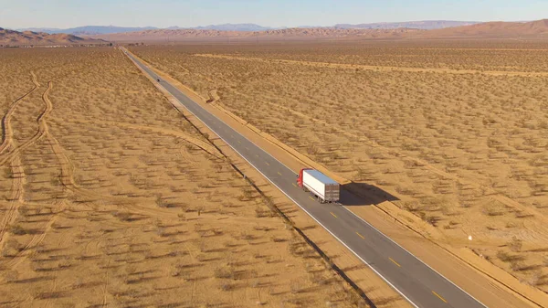 Vrachtwagen rijdt langs de snelweg die door de Mojave woestijn leidt.. — Stockfoto