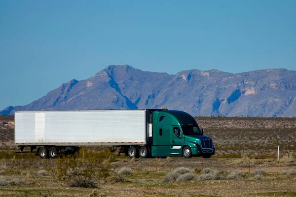CLOSE UP: Cool shot of barren landscape surrounding a green semi-trailer truck. — Stock Photo, Image