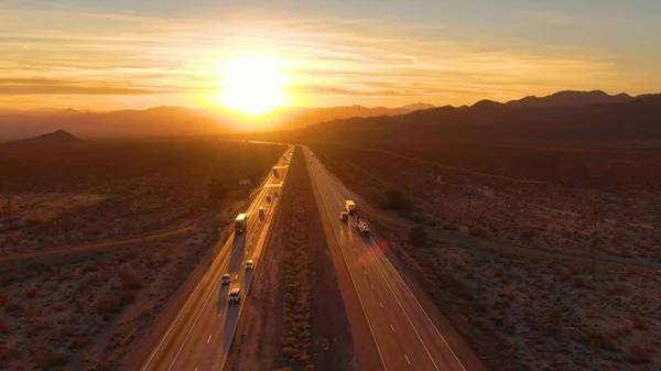 Сценарий 18 грузовиков и автомобилей, пересекающих пустыню Мохаве в сумерках — стоковое фото