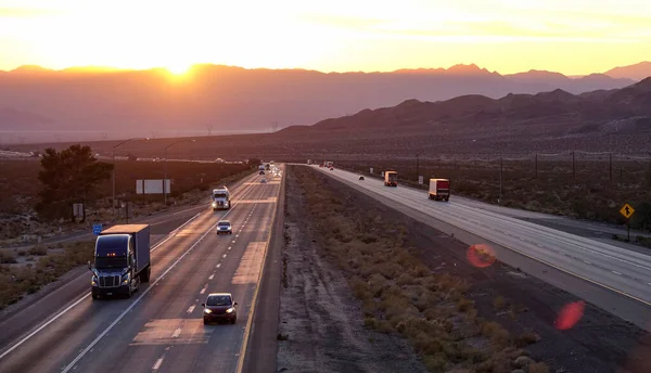 AERIAL: Scenic shot van 18 wheeler trucks en auto 's kruising Mojave woestijn in de schemering — Stockfoto