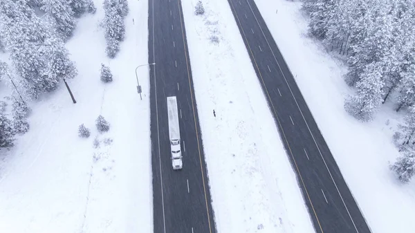 AERIAL: Voando acima de um caminhão que acelera ao longo da rodovia escorregadia durante uma nevasca . — Fotografia de Stock