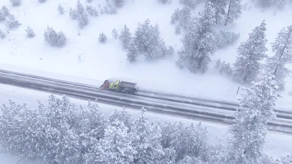 DRONE: Snow arado caminhão limpa a estrada do país que conduz através da floresta . — Fotografia de Stock