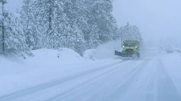 CLOSE UP: Lastbil plöjer den snöiga landsvägen under en fruktansvärd snöstorm. — Stockfoto