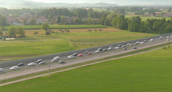 AERIAL: Gouden zomerzonnestralen schijnen op voertuigen die vastzitten in een file op de snelweg — Stockfoto