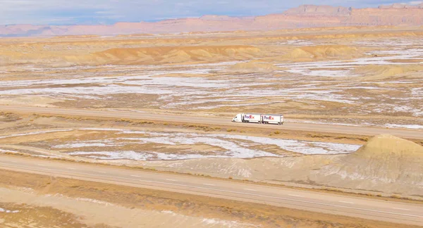 DRONE: Barre winterse landschap omringt een FedEx vrachtwagen rijden over Utah. — Stockfoto