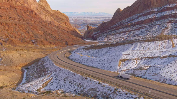 AÉRIAL : Vol derrière un camion transportant des marchandises à travers un canyon hivernal dans l'Utah. — Photo