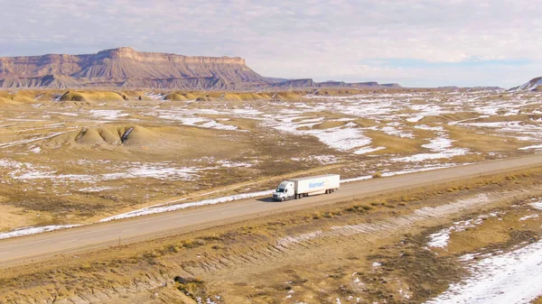 AERIAL: Caminhão Walmart transporta carga através do deserto de Utah em um dia ensolarado de inverno. — Fotografia de Stock