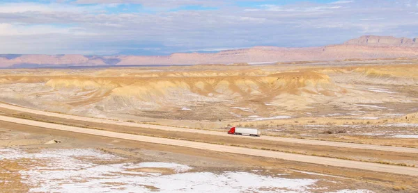 DRONE: camión semirremolque rojo lleva un contenedor pesado a través del desierto nevado. — Foto de Stock