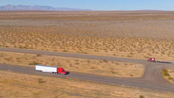 AERIAL: Latanie nad czerwoną ciężarówką towarową wytrzymującą długą podróż przez pustynię Utah. — Zdjęcie stockowe