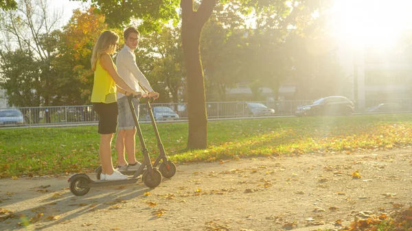 Lente FLARE Hombre y mujer hablan mientras disfruta de un paseo en scooter por la colorida avenida —  Fotos de Stock