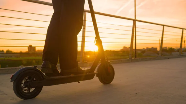 FLARE DE LA LENTE: El gerente monta un scooter eléctrico para trabajar en una soleada mañana de primavera. —  Fotos de Stock