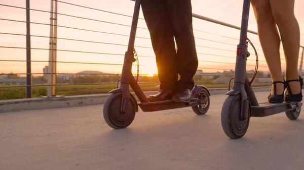 Resmi olarak iş arkadaşları gün doğumunda işe elektrikli scooterla giderler.. — Stok fotoğraf