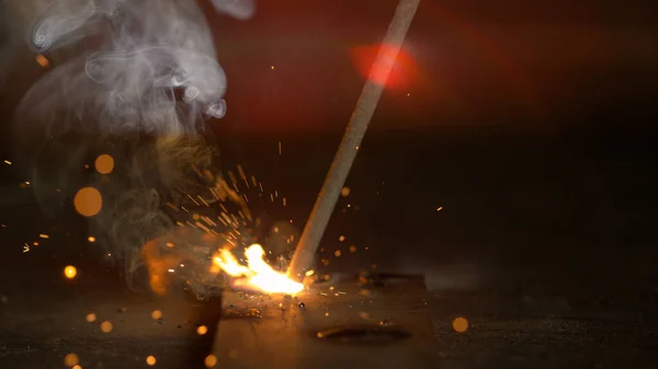 MACRO: El humo y las chispas vuelan de una soldadura como metalúrgico crea una pequeña soldadura. —  Fotos de Stock