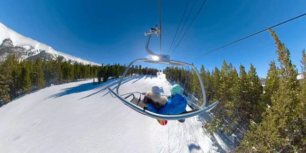 Les jeunes snowboarders montent le télésiège et observent la nature pittoresque par une journée ensoleillée — Photo