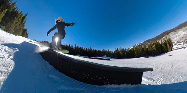 LENS FLARE: Donna attiva in vacanza con lo snowboard scivola lungo una ringhiera. — Foto Stock