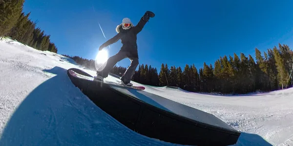 CLOSE UP: Action shot of female snowboarder sliding along a railing in snow park — Stock Photo, Image