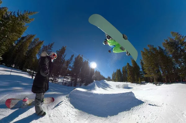 CLOSE UP: Kvinna är förvånad över snowboardåkare genom att fånga stor luft och göra ett trick — Stockfoto