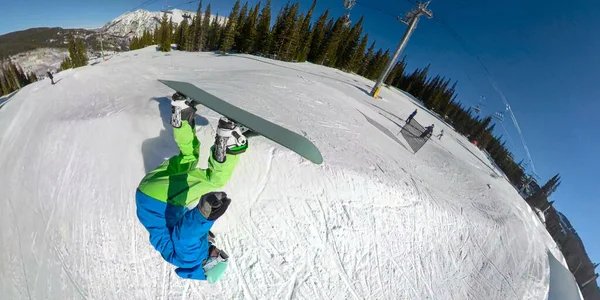 Freeride snowboarder profesional salta en el aire desde un pateador y hace una voltereta. — Foto de Stock