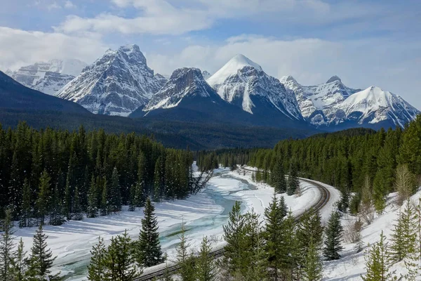 DRONE: Impresionante vista de una cresta cubierta de nieve que se eleva sobre un río congelado. — Foto de Stock