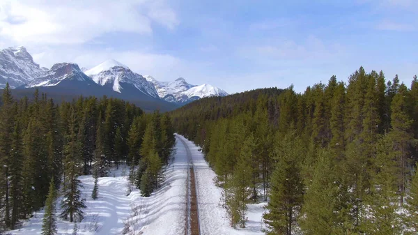 冬の山の下の森をリードする鉄道に沿って空飛ぶ — ストック写真