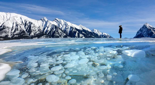 CERRAR: Turista femenina observa el lago congelado lleno de burbujas de metano. — Foto de Stock