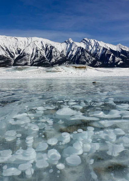 VERTICAL: Espectacular vista de una burbuja llena Lago Abraham bajo montañas nevadas — Foto de Stock