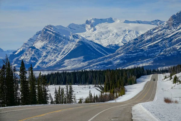 AERIAL: Scenic view of the snowy Rockies as car disappears in the distance. — ストック写真