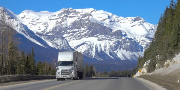 Vrachtwagen vervoert vracht over de snelweg naar besneeuwde bergen. — Stockfoto
