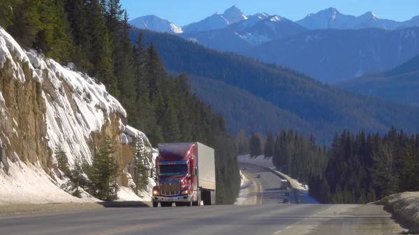 Rode vrachtwagen vervoert een container door het prachtige Jasper National Park. — Stockfoto