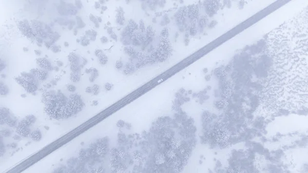 トップダウン:吹雪の中、雪の荒野を走る車の上を飛ぶ. — ストック写真