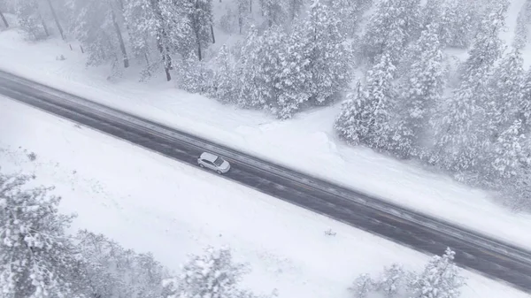 DRONE: Fotografia cinematográfica de um carro dirigindo por uma estrada vazia durante uma tempestade de neve — Fotografia de Stock