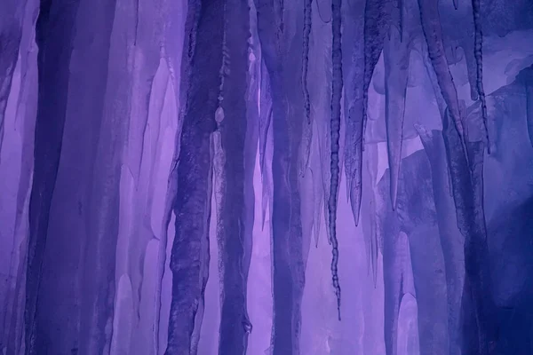 STÄNGA UPP: Långa glasartade isstalaktiter hänger från taket i en isig grotta. — Stockfoto