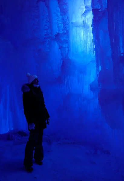 VERTICAL: Young woman exploring an icecave looks at a beautiful ice formation. — ストック写真