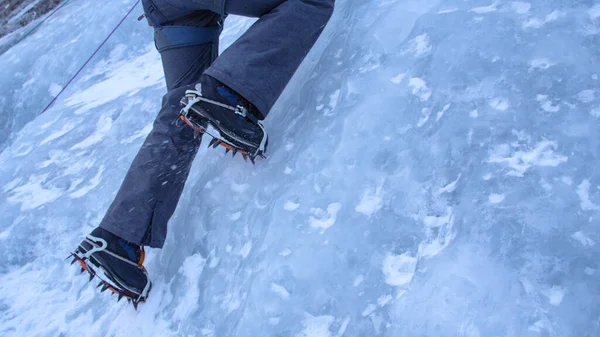 CLOSE UP Alpinist sticks her crampons in the ice while climbing up frozen stream Stock Image