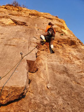 Dişi turistler tırmanırken, yüksek kayalık duvarın tabanından görüntüyü izleyin..