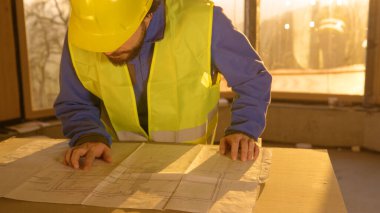 Tanımlanamayan mimar gün batımında inşaat planlarına bakıyor..