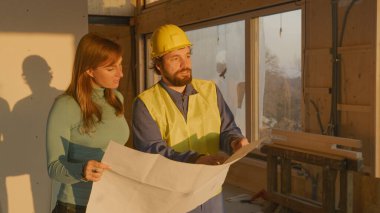 Mimar, inşaatın planlarını müstakbel genç ev sahibine açıklıyor..