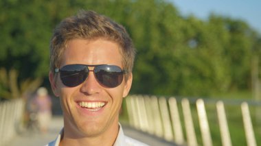 Kendinden emin işadamı güneşli bir günde parkta eğlenirken gülüyor..