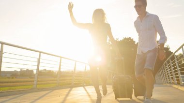 Genç turist çift bavullarıyla üst geçitten geçiyor..