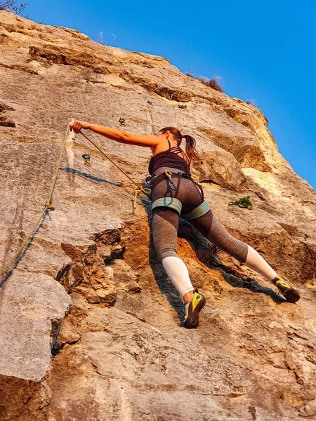VERTICAL: Unrecognizable female rock climber scales a wall on a sunny evening. — ストック写真