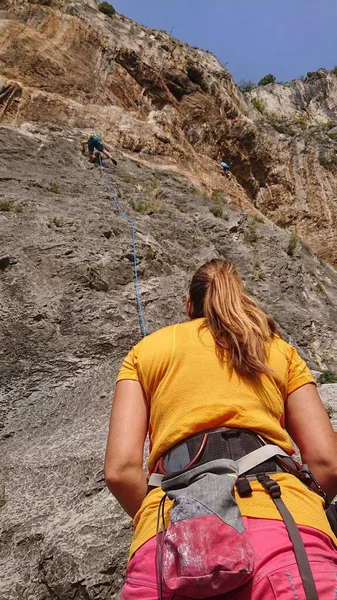CLOSE UP: Unrecognizable woman looks up at friends climbing up a rocky wall. — ストック写真